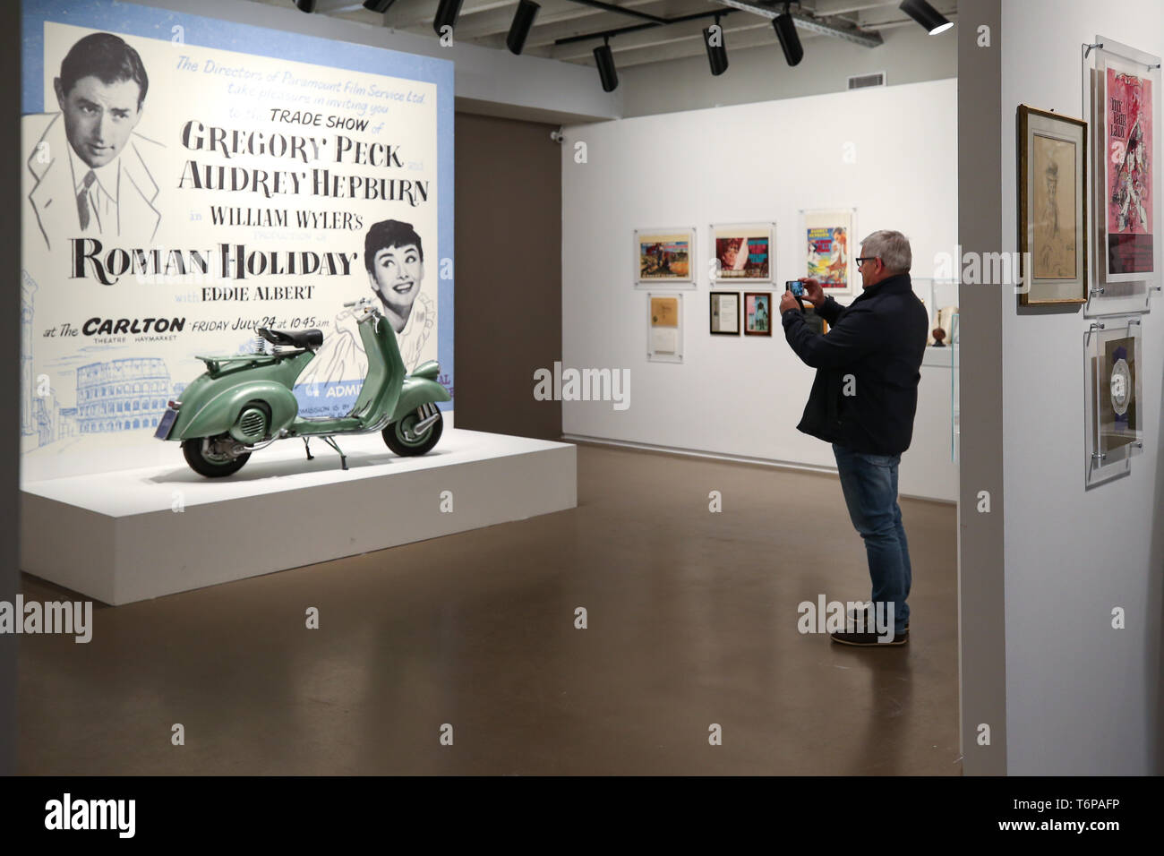 Bruxelles, Belgio. Il 1 maggio, 2019. Un visitatore prende le immagini della moto utilizzata da Audrey Hepburn nel film Vacanze Romane presso la mostra 'intima Audrey' a Bruxelles, Belgio, 1 maggio 2019. 'Intima Audrey' è una mostra su Audrey Hepburn creato da suo figlio Sean Hepburn Ferrer, per festeggiare il suo novantesimo compleanno nel suo luogo natale di Bruxelles. La mostra, concentrandosi sulla vita di Audrey Hepburn attraverso fotografie, souvenir, abiti e accessori, sono iniziate il 1 maggio e durerà fino al 25 agosto. Credito: Zhang Cheng/Xinhua/Alamy Live News Foto Stock