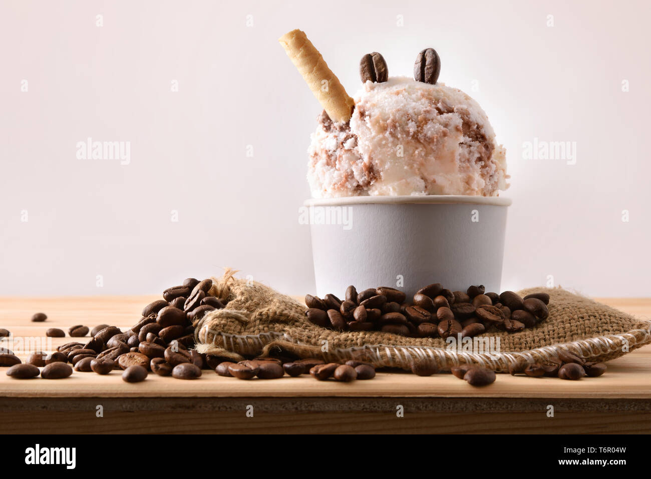 Gelato al caffè Tazza decorata con grani e waffle sul sacco di stoffa su un tavolo di legno. Composizione orizzontale. Vista frontale. Foto Stock