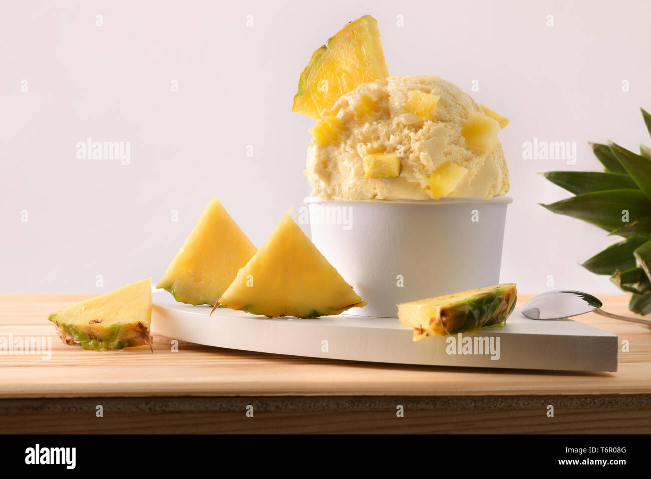 Ananas coppa di gelato decorata con pezzi di ananas e segmenti su di un tavolo di legno. Composizione orizzontale. Vista frontale. Foto Stock