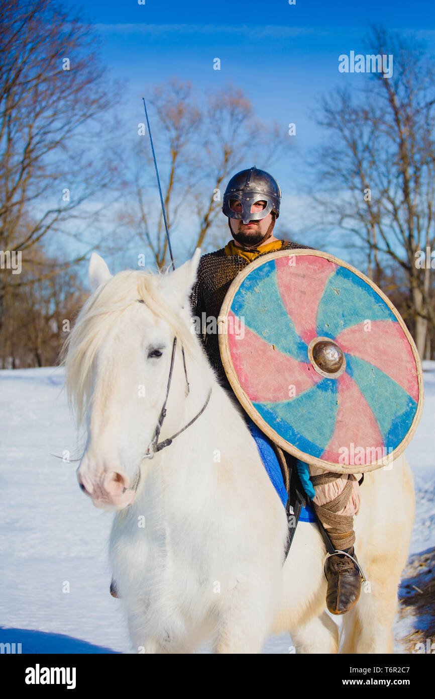 Uomo in tuta di antiche viking riding big White Horse Foto Stock