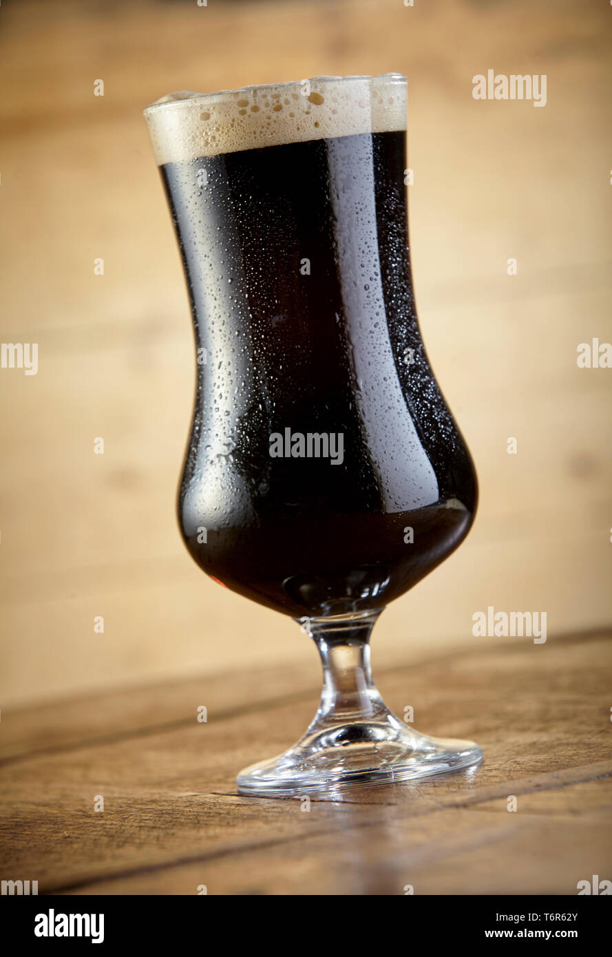 Vista ravvicinata di fresca birra Stout calice in piedi sulla tavola contro lo sfondo di legno Foto Stock