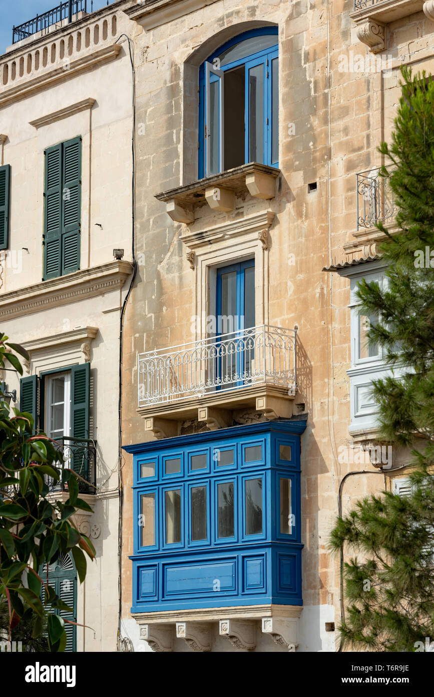 Una tradizionale casa Maltese in mulino a vento St con balconi contrastanti: un vibrante blu racchiuso galleriji, ferro battuto enclosure e pianura battuta. Foto Stock
