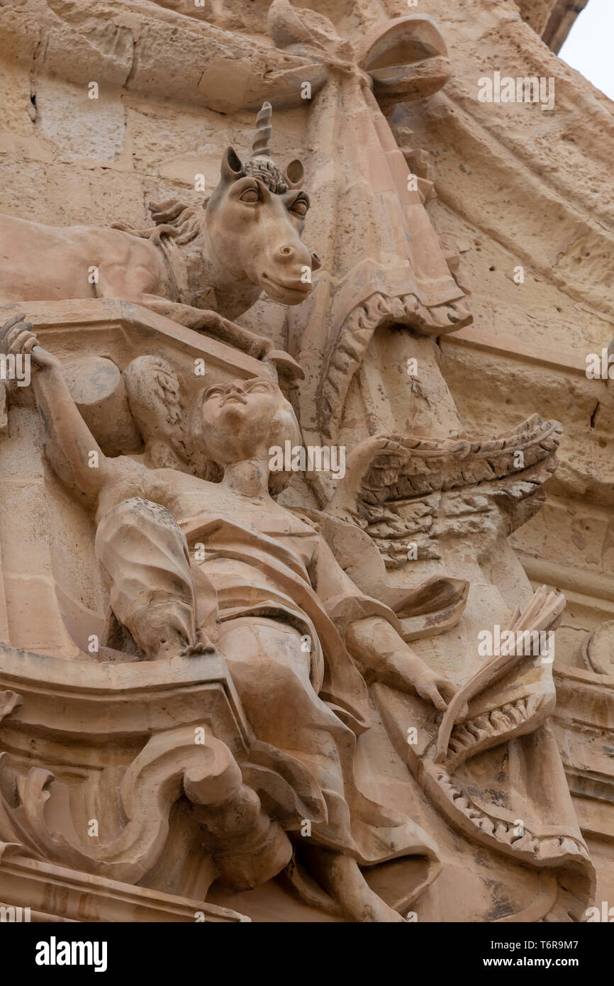 Una scultura di un angelo che guarda su un unicorno in posizione supina su un edificio a Malta Foto Stock