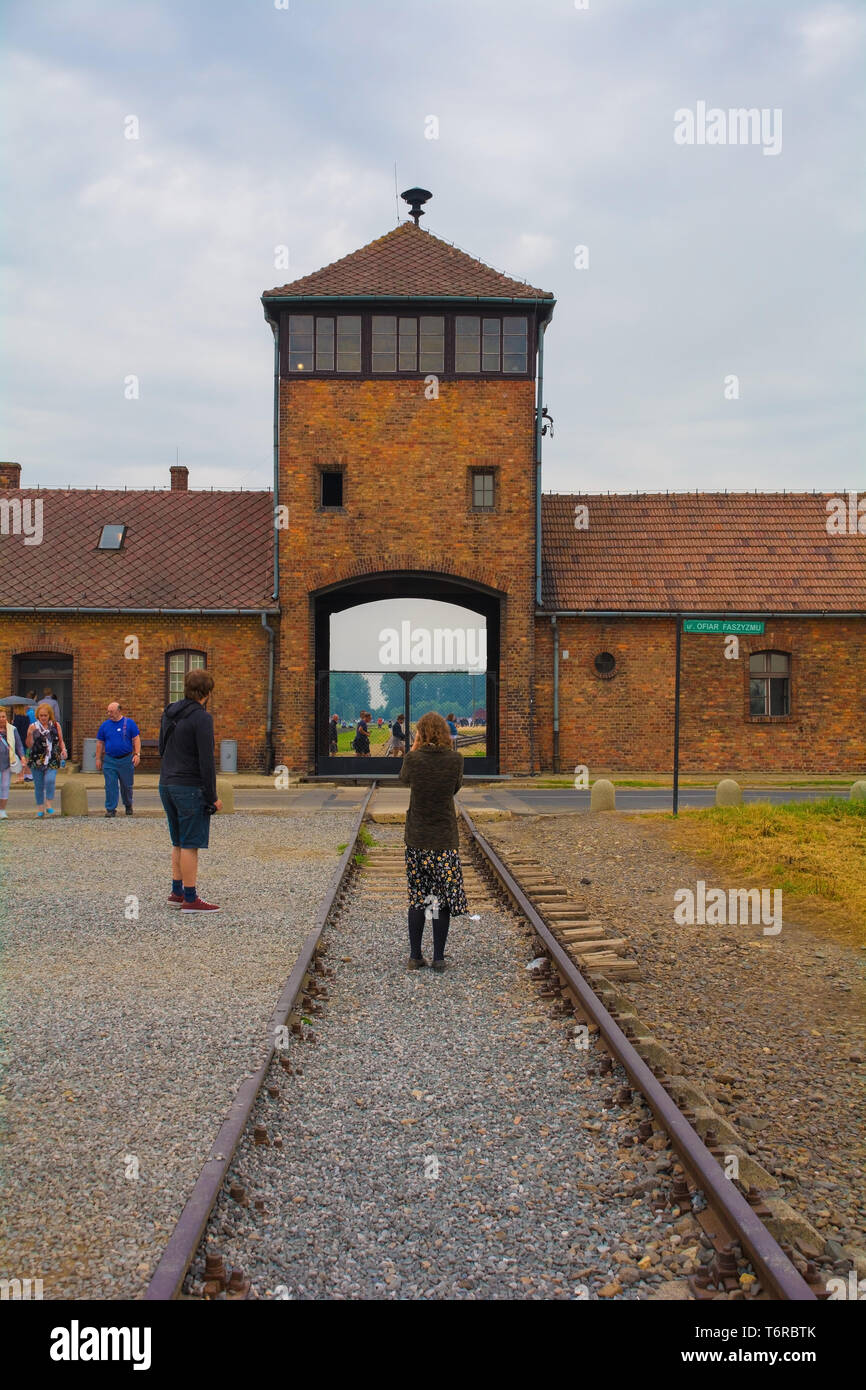Oswiecim, Polonia - 11 luglio 2018. Un visitatore prende le fotografie dell'ingresso principale e la torre di guardia al Birkenau-Auschwitz II campo di concentramento Foto Stock