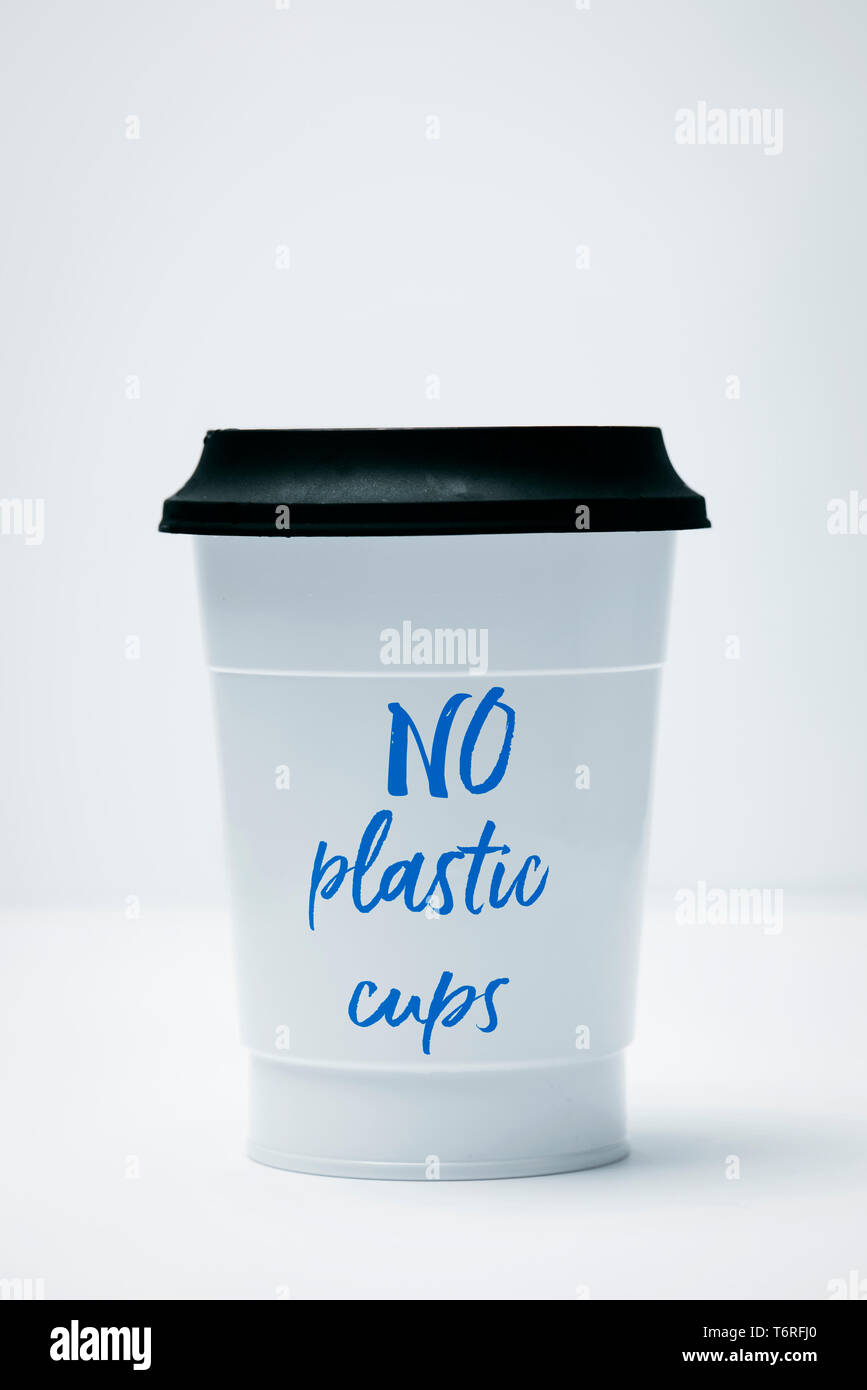 Primo piano di un bianco tazza di plastica con il testo non bicchieri di plastica scritto in esso, coperto con un coperchio nero su sfondo bianco Foto Stock