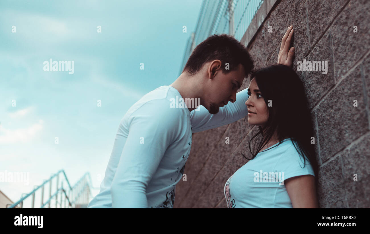 Giovani coppie amorevole in piedi accanto al muro di mattoni, felice e soddisfatto, il concetto di stile di vita Foto Stock