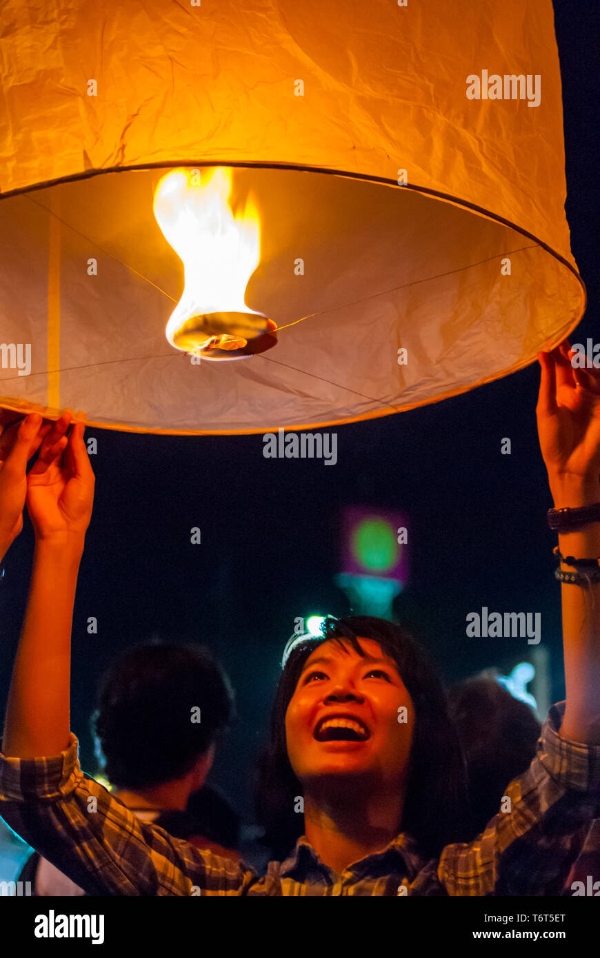 Chiang Mai, Thailandia - Nov 2015: una giovane donna fulmine fino una lanterna per rilasciarla durante il Loy Krathong festival in Chiang Mai Foto Stock