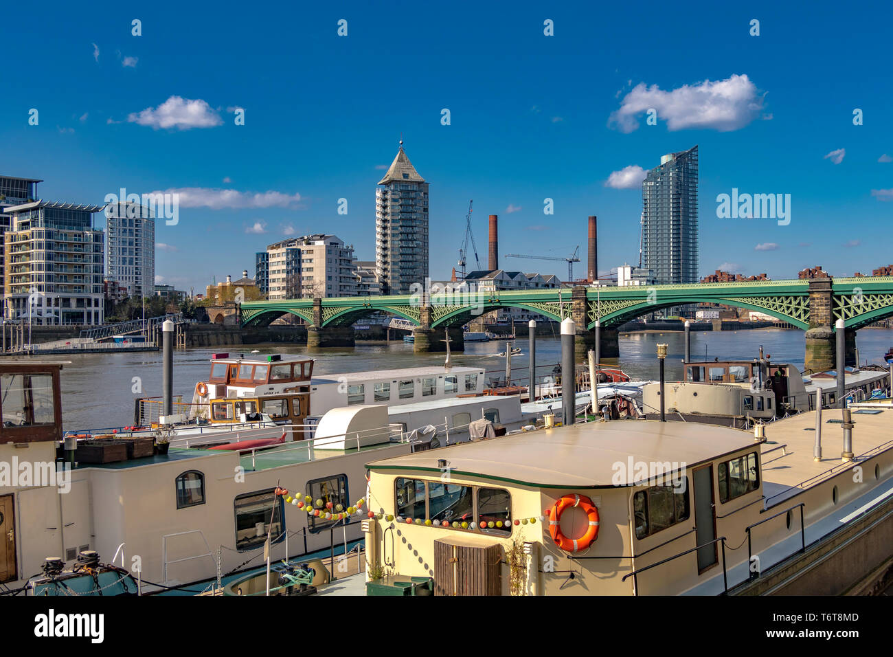 Houseboats lungo il Tamigi a Battersea con Battersea Railway Bridge e Chelsea Harbour sullo sfondo, Londra, Regno Unito Foto Stock