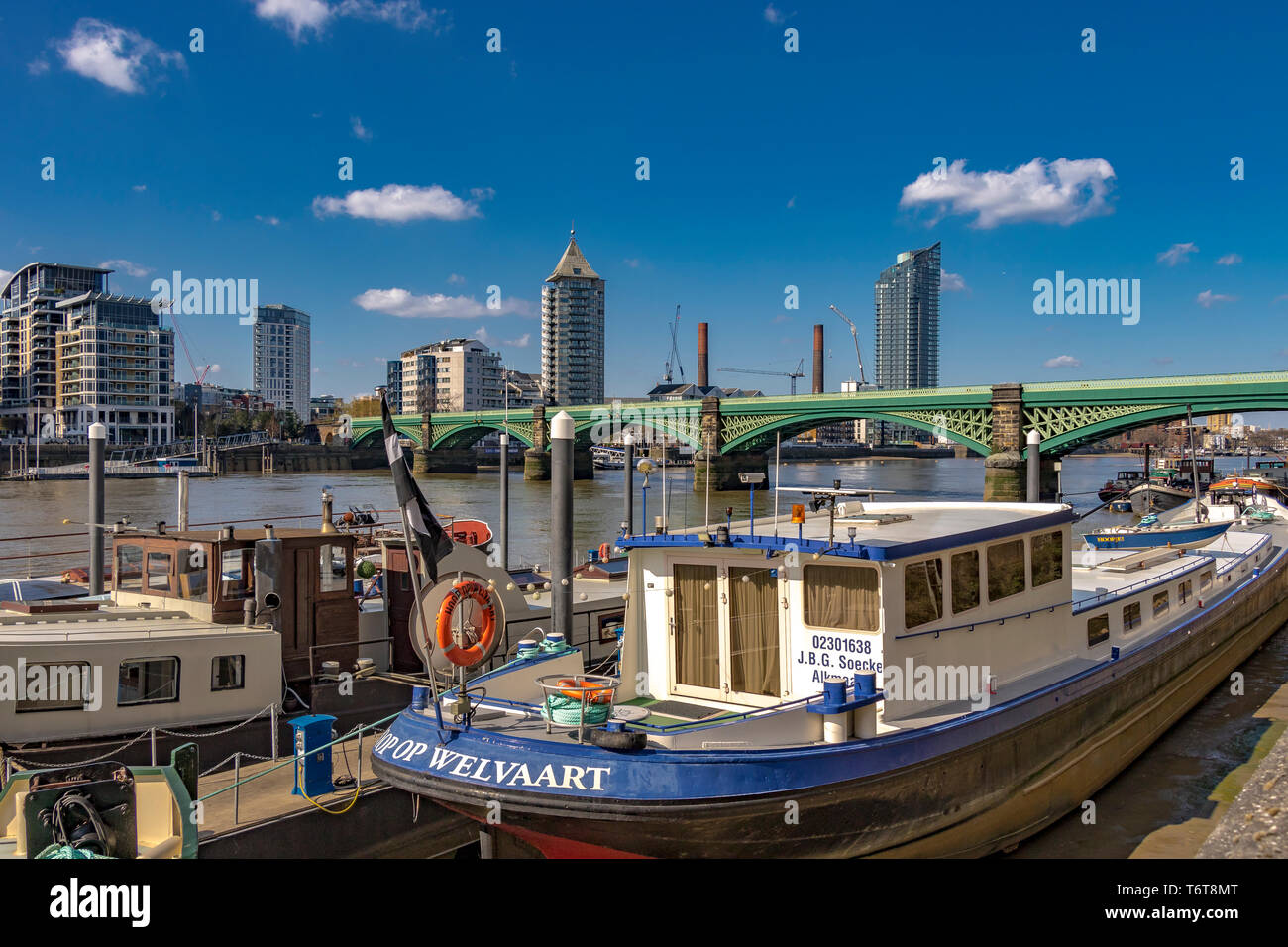 Houseboats lungo il Tamigi a Battersea con Battersea Railway Bridge e Chelsea Harbour sullo sfondo, Londra, Regno Unito Foto Stock