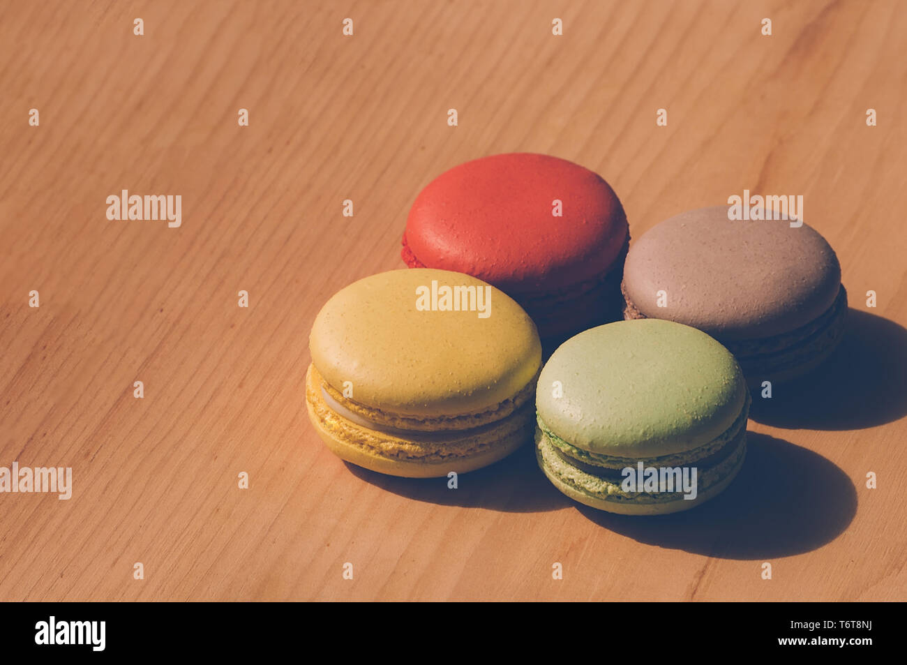 Quattro gustosi colorati macarons francese isolato su texture di legno Foto Stock
