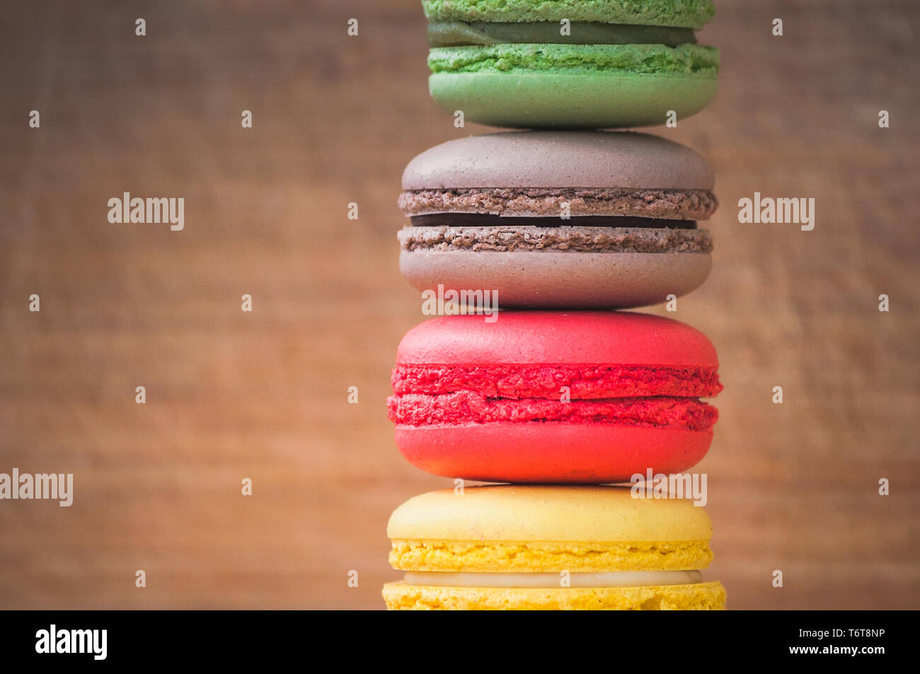 Quattro gustosi colorati macarons francese isolato su texture di legno Foto Stock