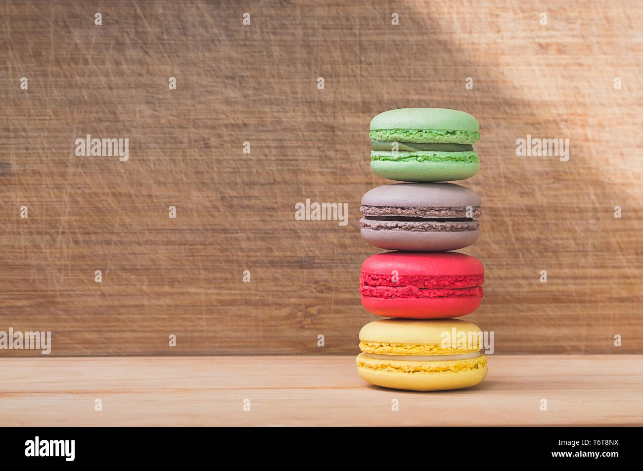 Quattro gustosi colorati macarons francese isolato su texture di legno Foto Stock