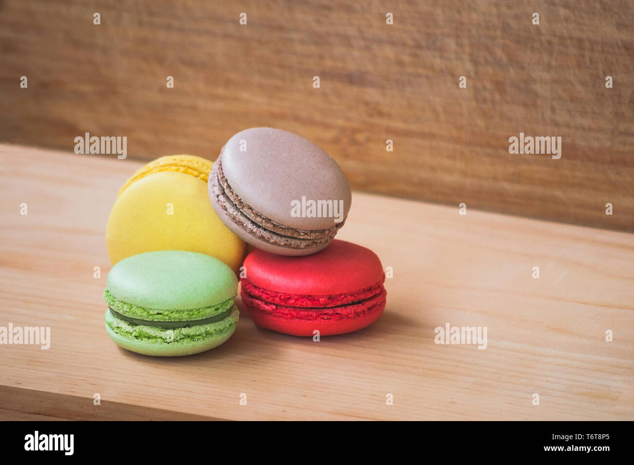 Quattro gustosi colorati macarons francese isolato su texture di legno Foto Stock