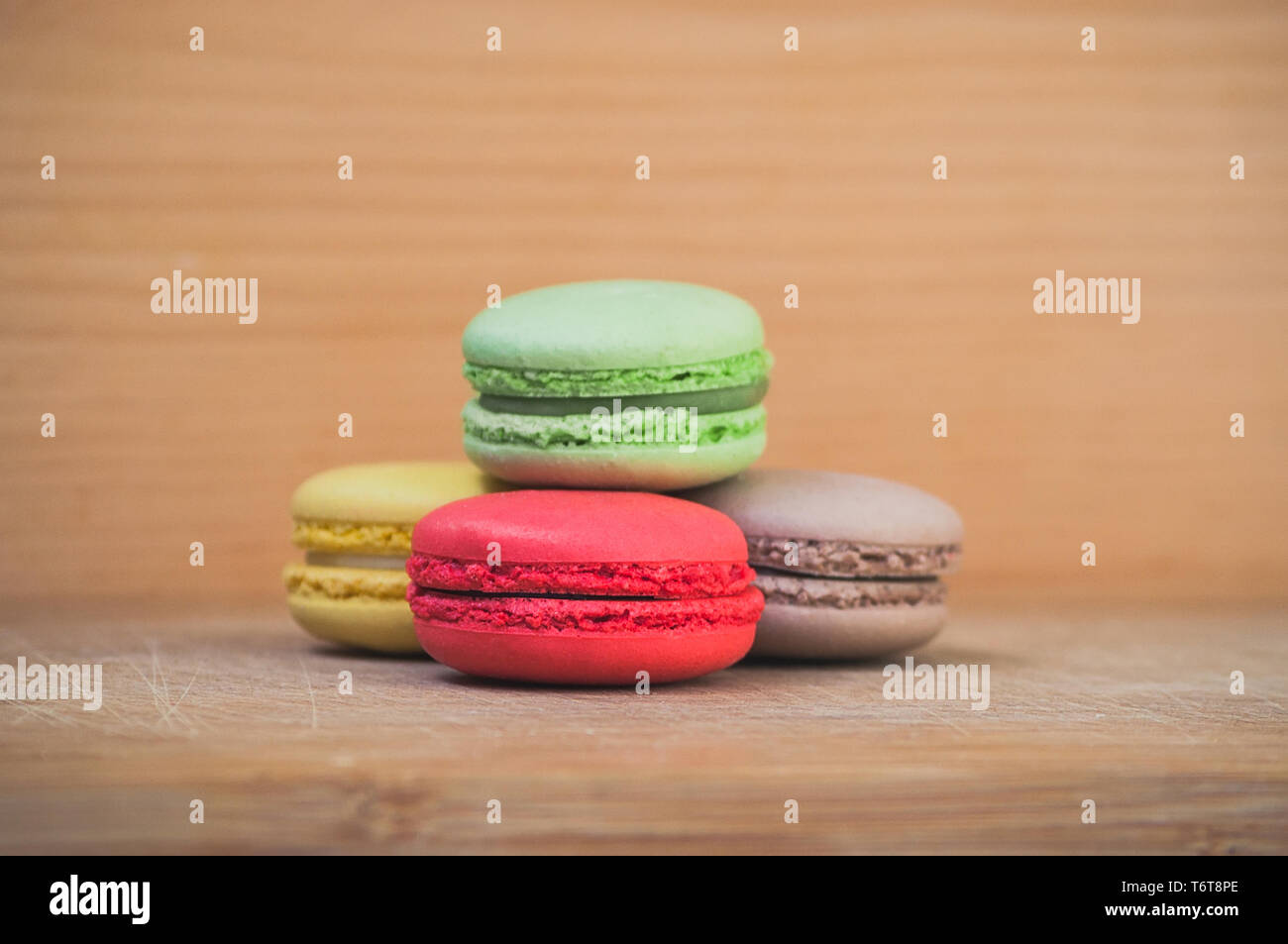 Quattro gustosi colorati macarons francese isolato su texture di legno Foto Stock