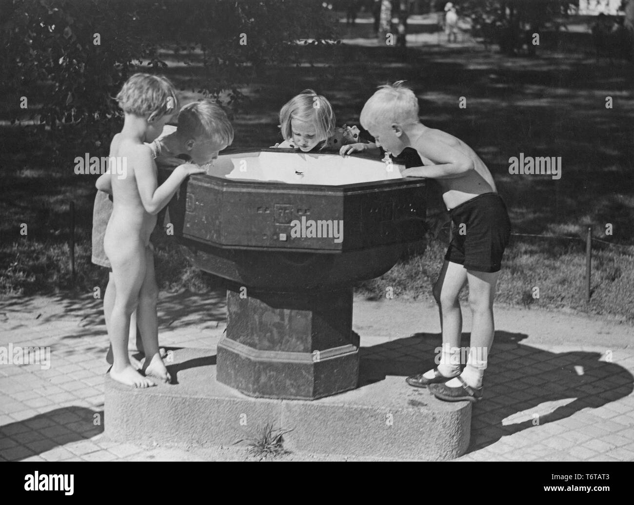 Estate di 1940s. Quattro bambini sono acqua potabile da una fontana di acqua in uno dei parchi di Stoccolma. Queste fontane pubbliche erano comuni e in questo momento è azionato spingendo la leva verso il basso e che l'acqua ha iniziato a flusso. La Svezia 1940s Foto Stock