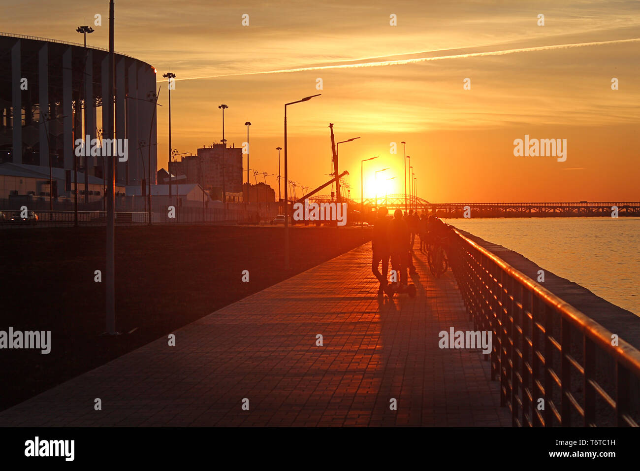 Sagome di persone contro il tramonto sulla riva del fiume Foto Stock