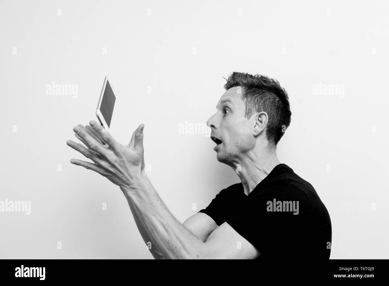 Sorpreso l uomo è far cadere il suo telefono, deve sostituire la rottura cellulare Foto Stock