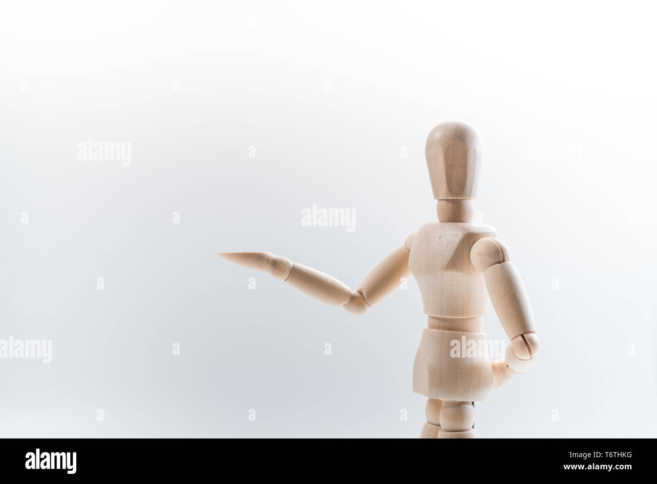 Manichino di legno con orgoglio presenta qualche cosa invisibile, isolato su sfondo bianco, copia dello spazio per il vostro oggetto o testo Foto Stock
