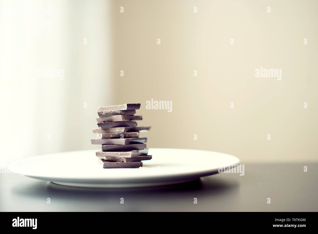 Cioccolato fondente impilate su di una piastra. Colori crema, toni morbidi con filtro sbiadito e sfondo neutro. RF / alimentare vegano concetto di stile di vita. Foto Stock