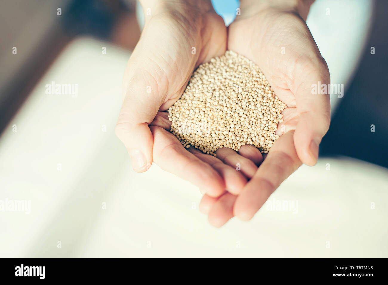 Close up della donna e delle sue mani tenendo la quinoa. Colori vivaci e tonalità delicate con filtro sbiadito. RF pietanze senza glutine / super / vegano concetto di stile di vita. Foto Stock