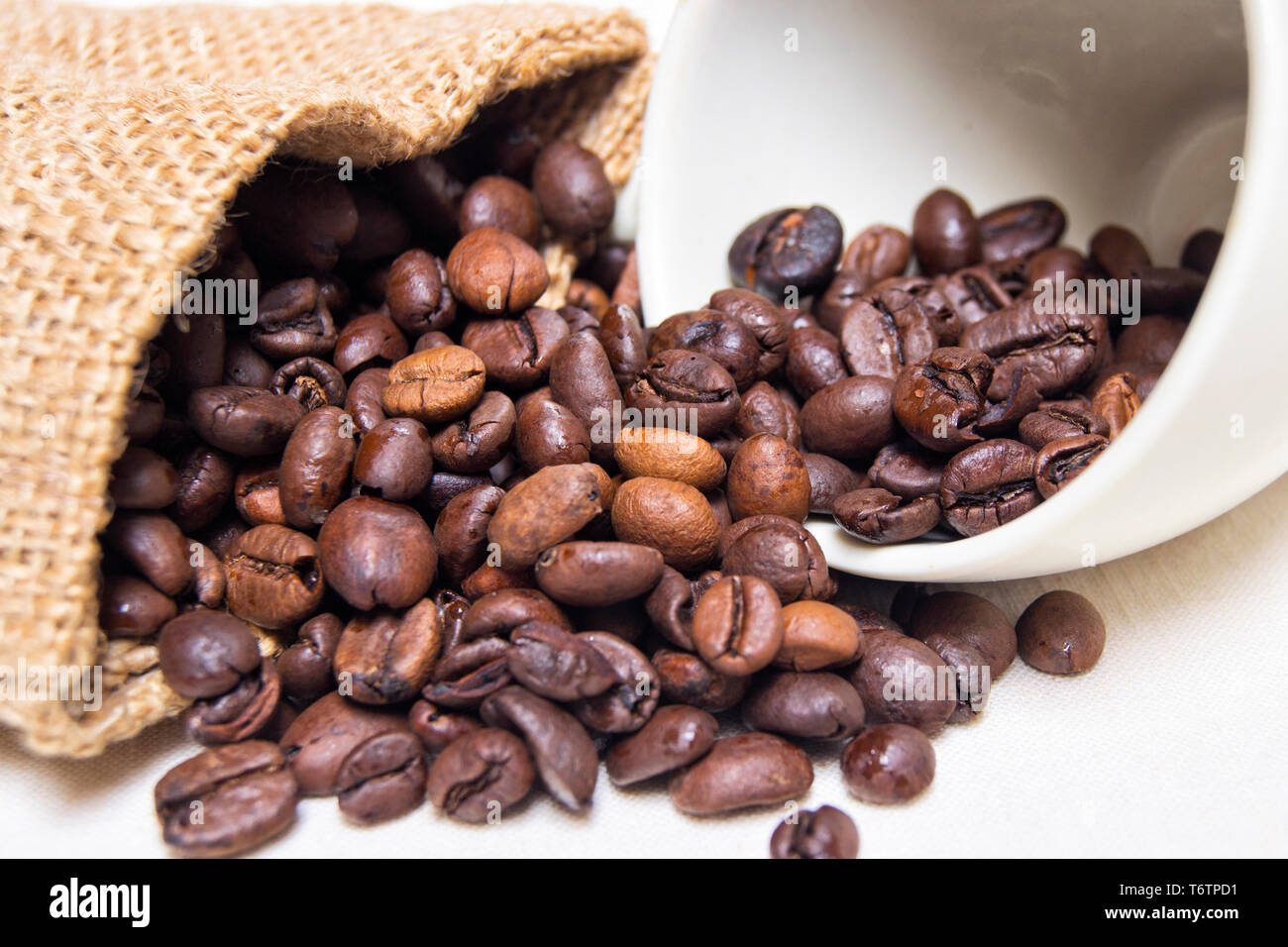 Chicchi di caffè tostati con materie tessili e di colore bianco porcellana tazza da caffè Foto Stock