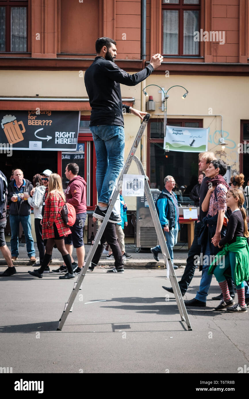 Berlino, Germania - 01 May 2019:uomo in piedi sulla scala di scattare una foto con il telefono cellulare sulla street parade il giorno della festa del lavoro a Berlino Foto Stock