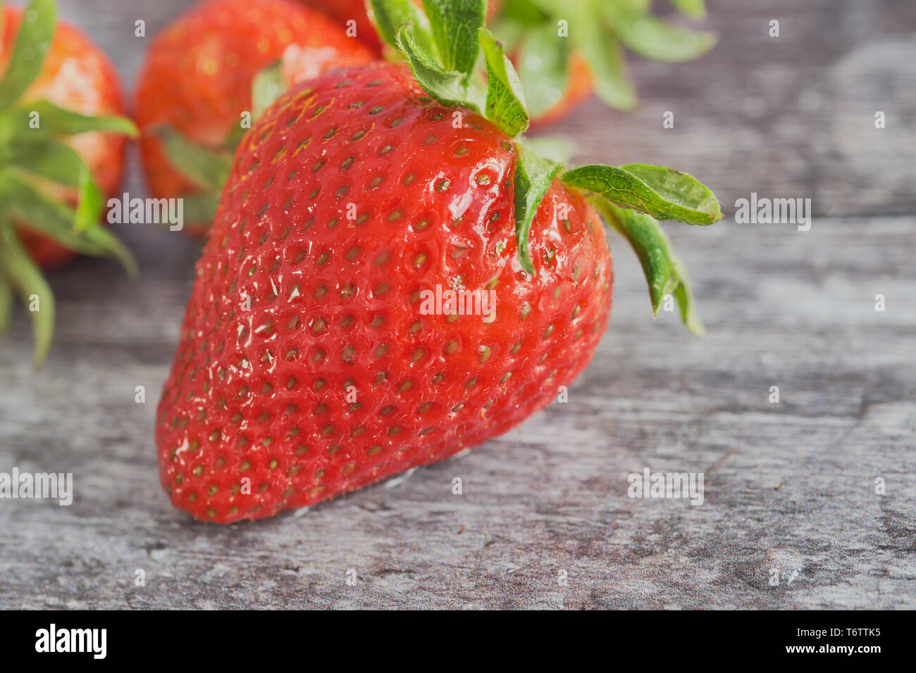 Fragole su uno sfondo di legno, macro foto a colori con una fragola nella parte anteriore Foto Stock