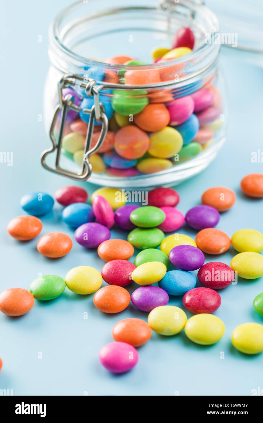 Cioccolato colorato candy pillole su sfondo blu. Foto Stock