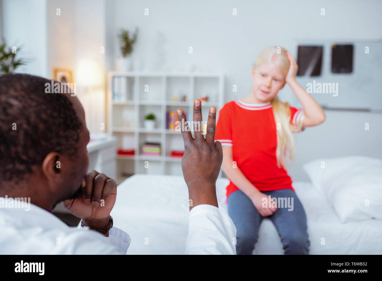 Di carnagione scura medico mostra ragazza con commozione tre dita Foto Stock