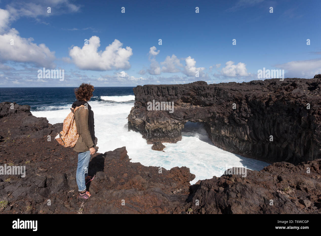 20 30 anni ragazza in piedi su una scogliera con big surf sotto Foto Stock