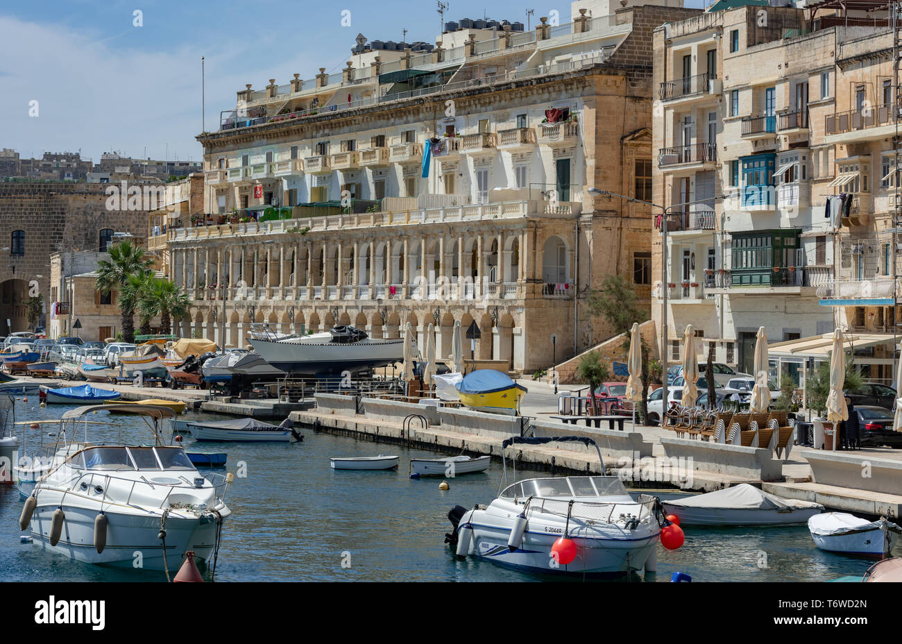 Barche a motore bianche e imbarcazioni da diporto nel Grand Harbour Marina di Vittoriosa, con gli storici edifici calcarei di Senglea che costeggiano il lungomare Foto Stock
