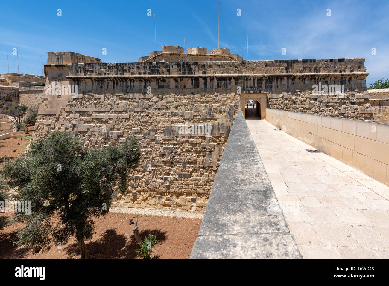 Il-Kwartier attraversa il fosso verso un arco nella parete del Bastione di San Giacomo, parte delle fortificazioni storiche di il-Birgu a Malta Foto Stock