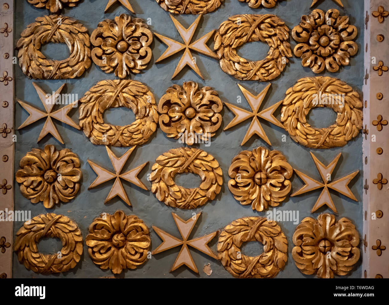 Dettaglio dei motivi dorati di ghirlande e croci maltesi scolpite nel morbido calcare maltese nella Co-Cattedrale di San Giovanni, la Valletta. Foto Stock