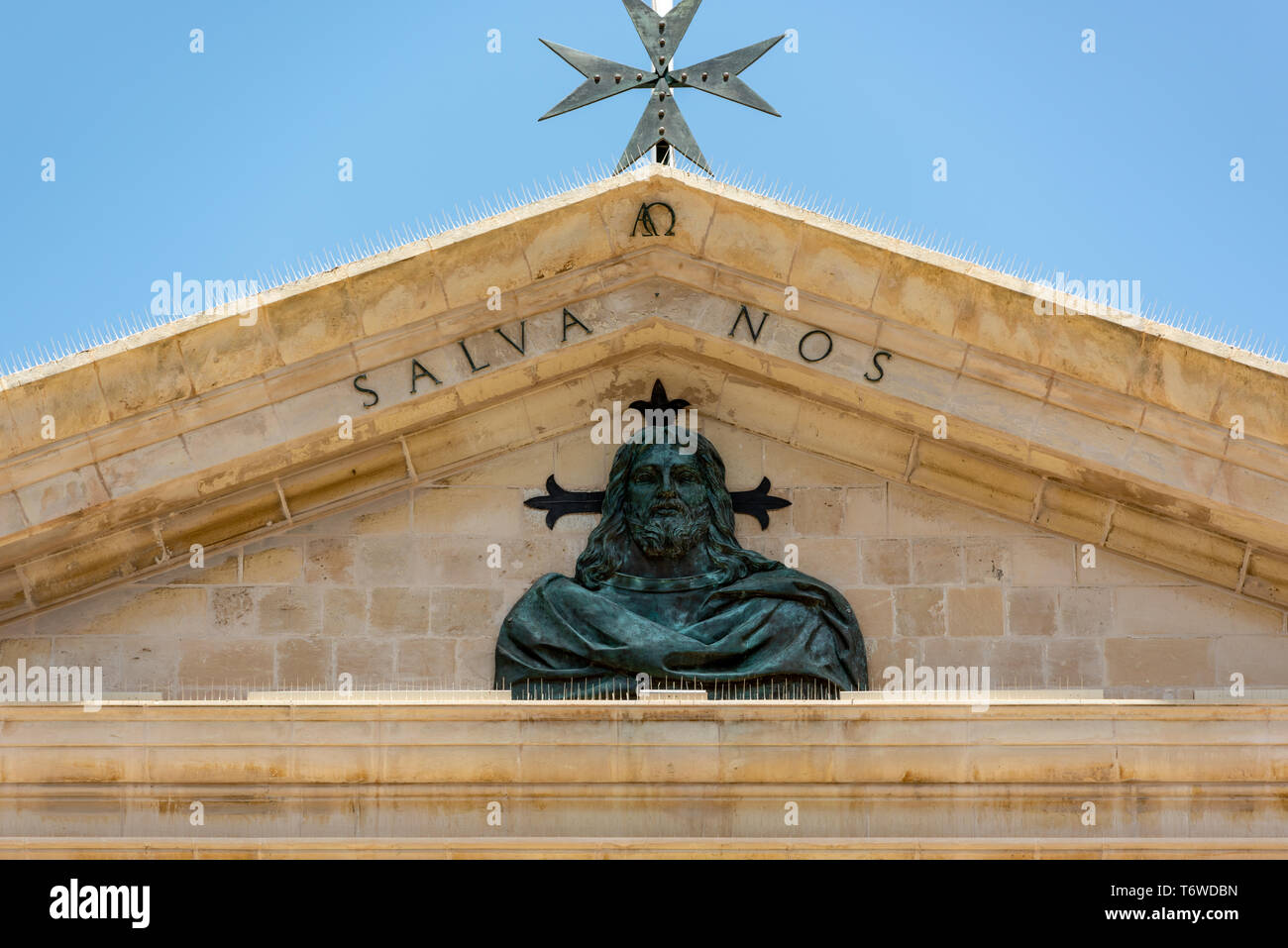 Particolare del frontone sopra il balcone sulla facciata della Concattedrale di San Giovanni di la Valletta con il rilievo di Gesù Cristo e la Croce di San Giovanni Foto Stock