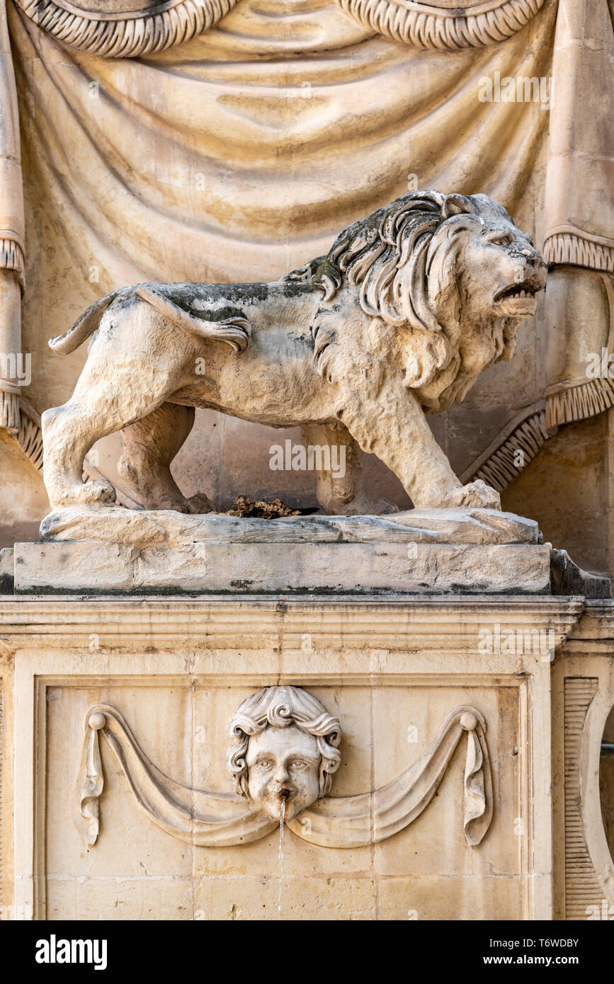 Un leone di pietra scolpito sopra una fontana d'acqua sul muro di un edificio a Triq San Gwann, (strada di San Giovanni), a la Valletta Foto Stock