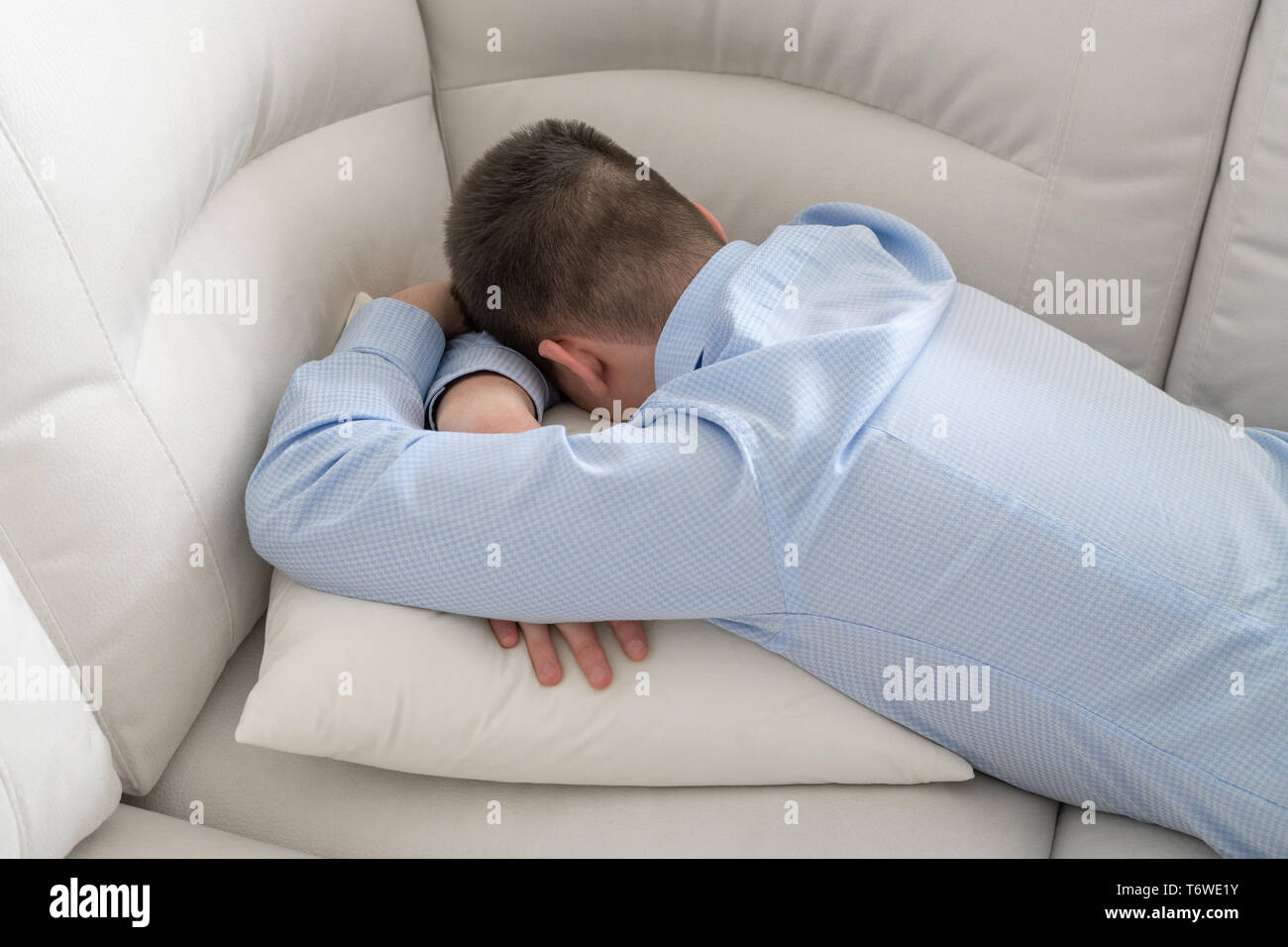 Premuto adolescente sdraiato a faccia in giù sul divano Foto Stock