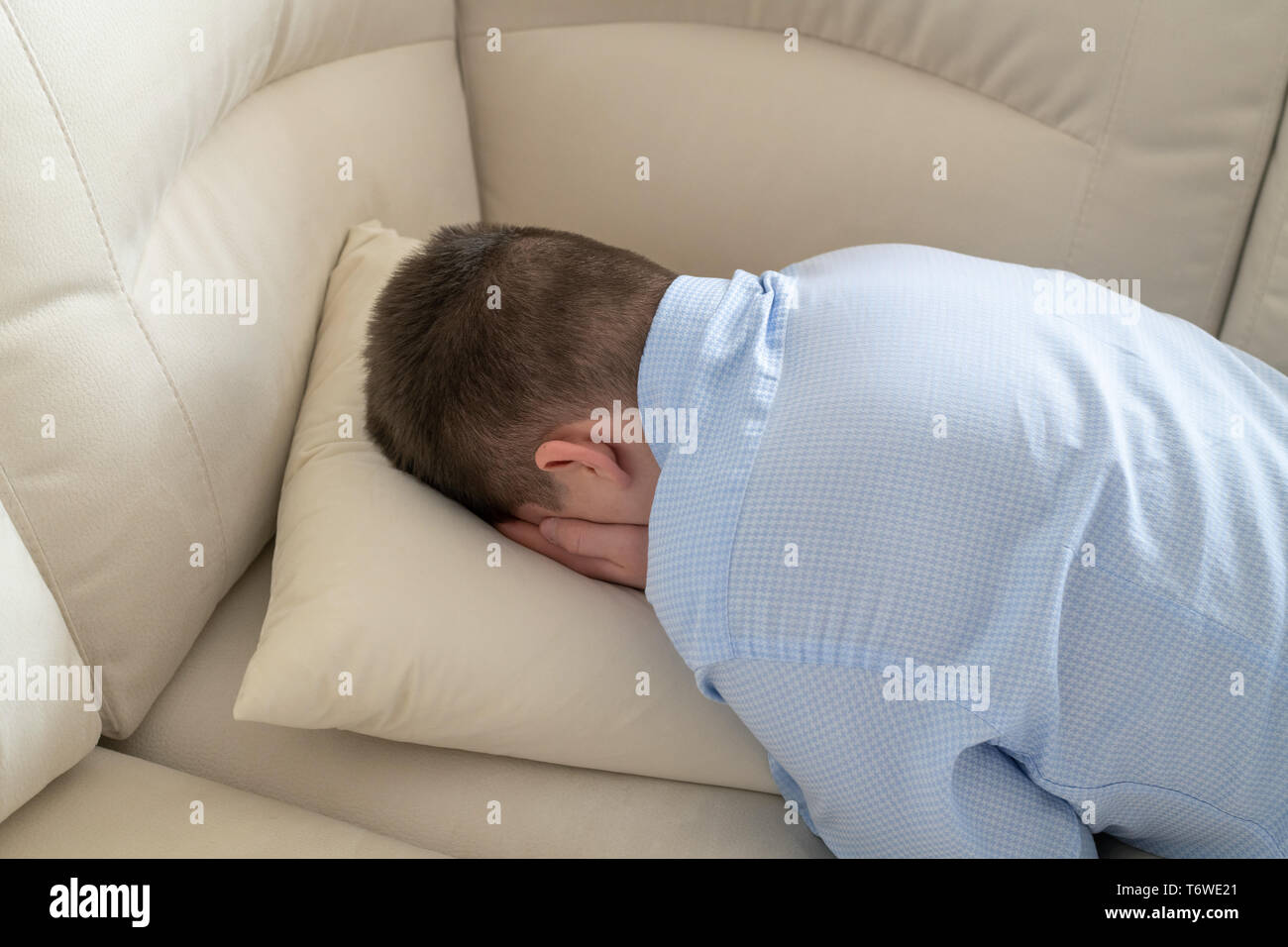 Premuto adolescente sdraiato a faccia in giù sul divano Foto Stock