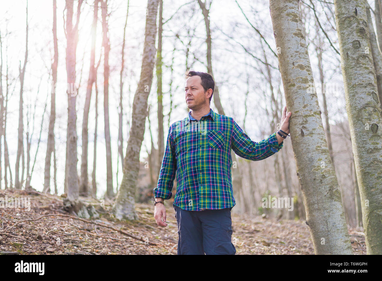 Vista anteriore dell'uomo in piedi nella foresta, mentre guardando lontano nella giornata di sole Foto Stock