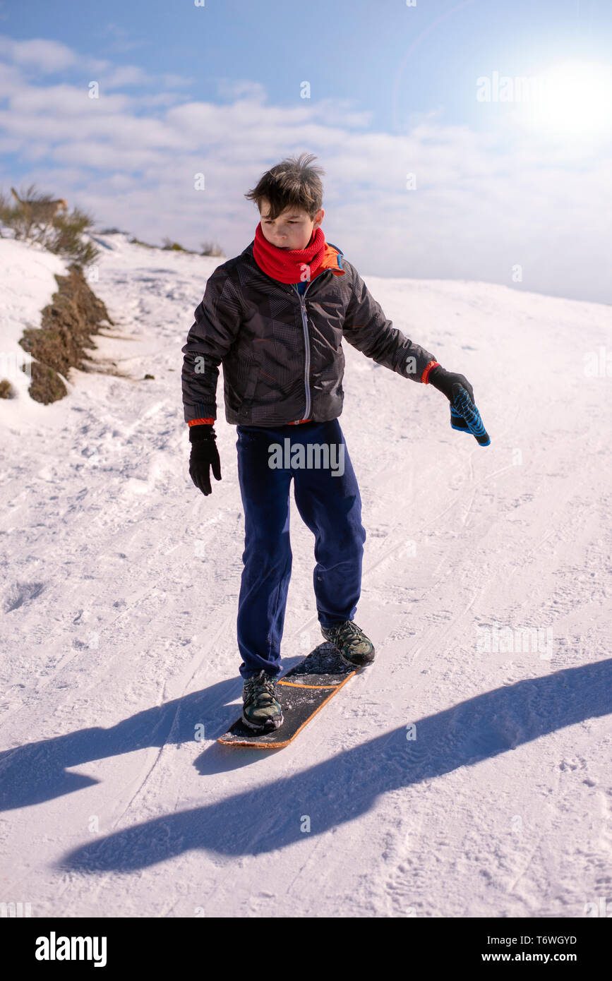 Vista frontale del ragazzo lo snowboard su skateboard in una coperta di neve hill Foto Stock