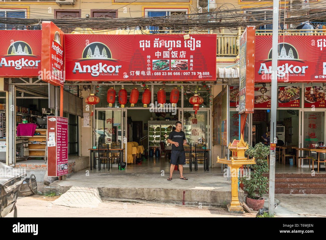 Sihanoukville, Cambogia - Marzo 15, 2019: bianco su rosso grande schede di pubblicità per la birra di Angkor sulla sommità op del livello del suolo di ristoranti e negozi al dettaglio sto Foto Stock