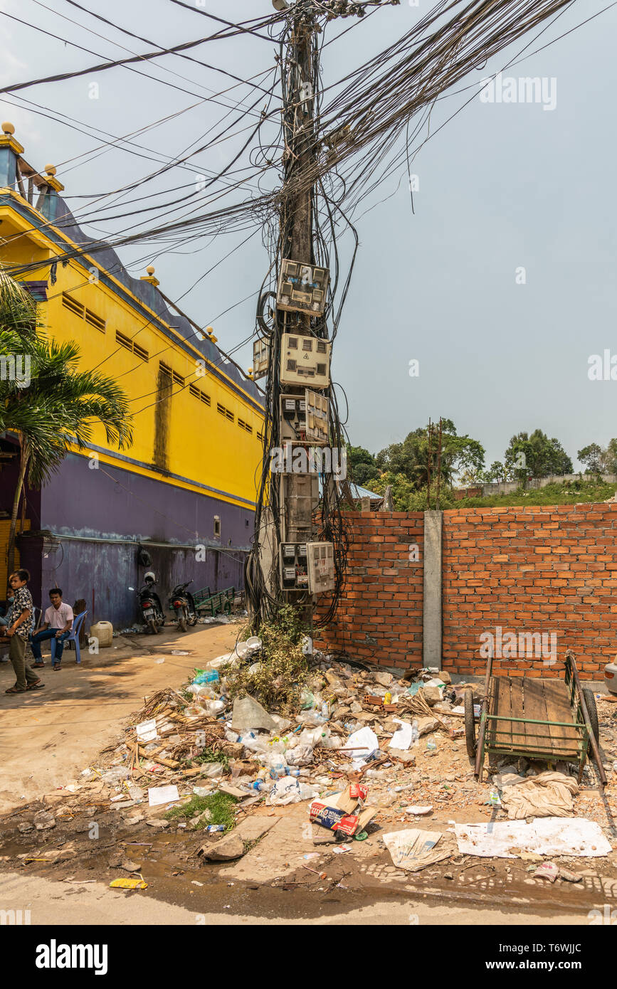 Sihanoukville, Cambogia - Marzo 15, 2019: Potenza pole catturato in un caotico cavi e aprire il fusibile e scatole di connessione, sorge sulla sommità della pila del cestino. Foto Stock