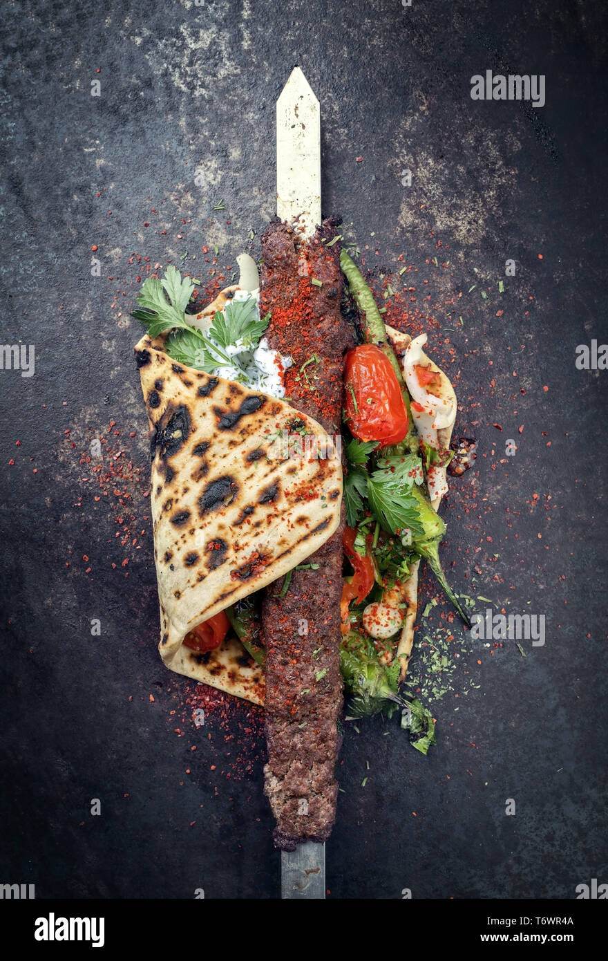 Tradizionali di Adana kebap su uno spiedino con pomodoro e yogurt come vista dall'alto su un flatbread Foto Stock