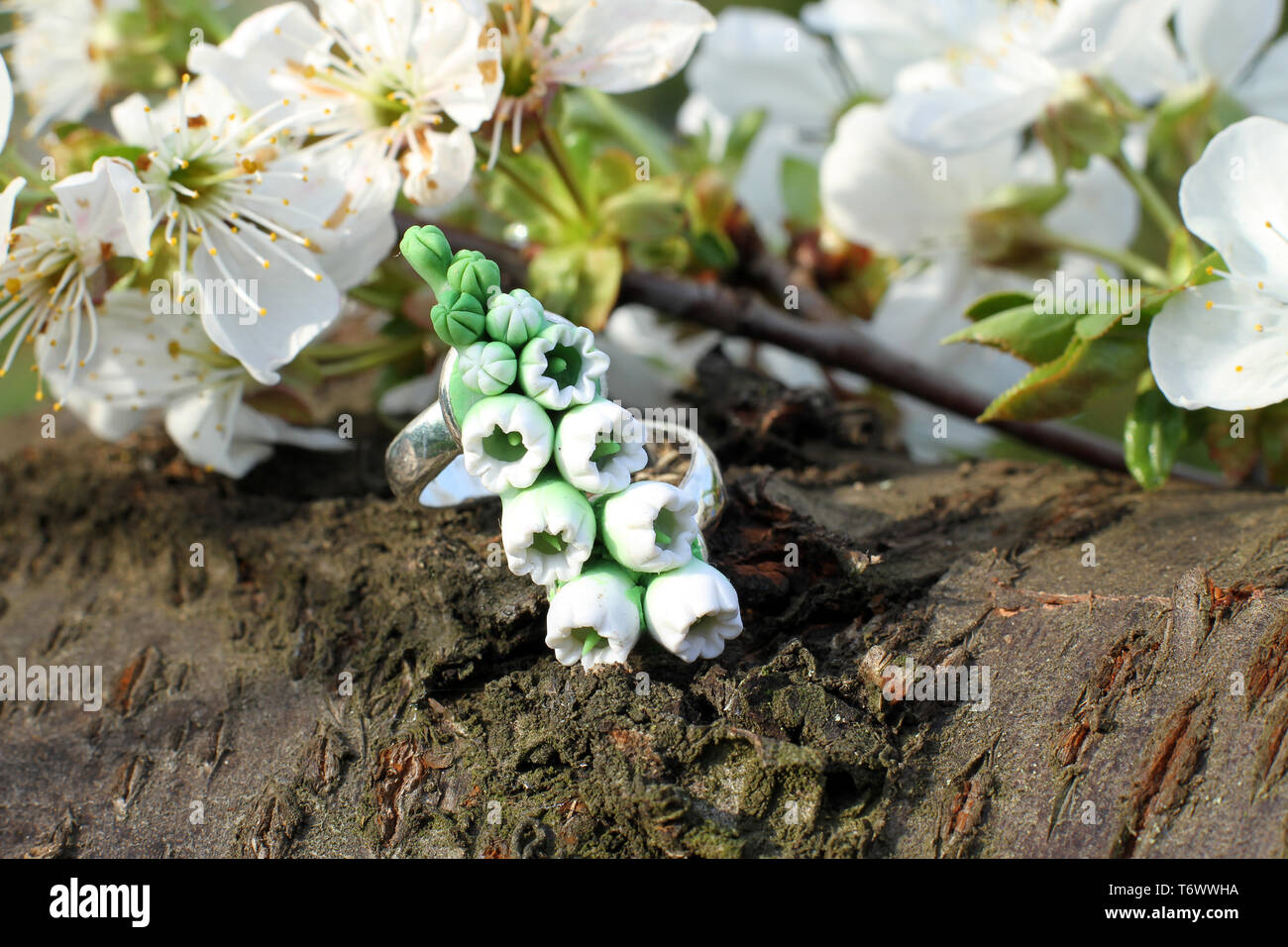 Un fatto a mano anello in una forma di fiori da polymer clay su sfondo di legno Foto Stock