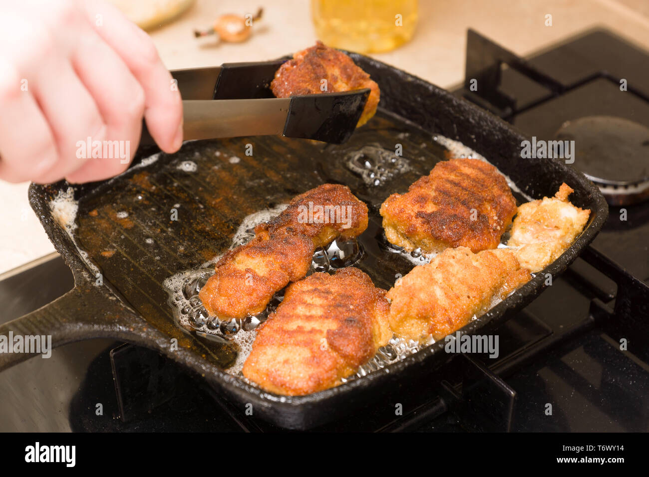 Pepite di cottura da freschi a base di carne di pollo su un caldo cast-padella di ferro Foto Stock