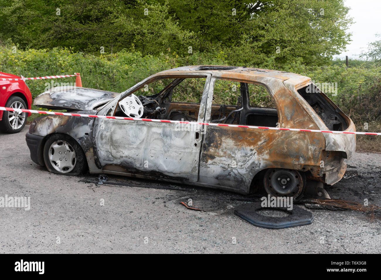 Bruciata auto abbandonate in un paesaggio car park, Regno Unito Foto Stock