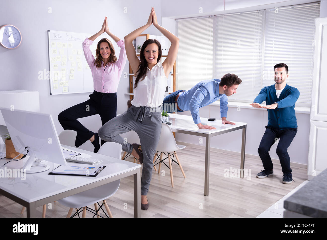 Sorridente Giovani Imprenditori fare yoga in ufficio Foto Stock