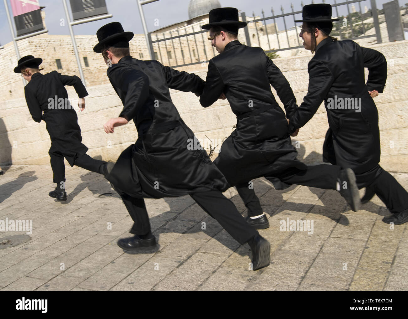 I ragazzi ebrei vestiti di nero tradizionali cappelli e cappotti sono in  esecuzione tenendo le mani Foto stock - Alamy