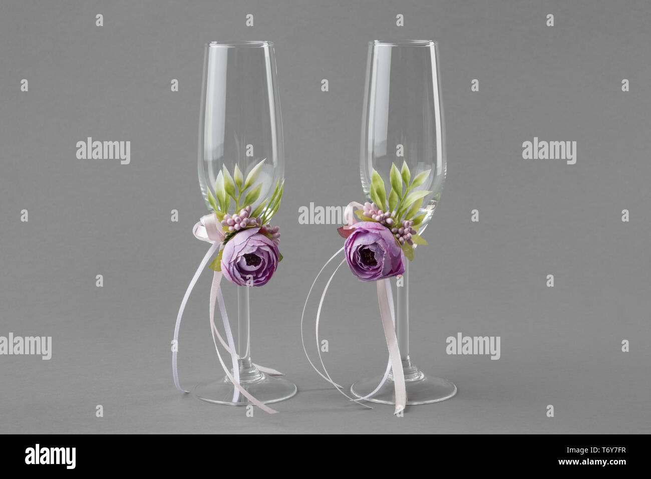Matrimonio di due bicchieri di vino decorate con fiori viola e nastri. Foto Stock