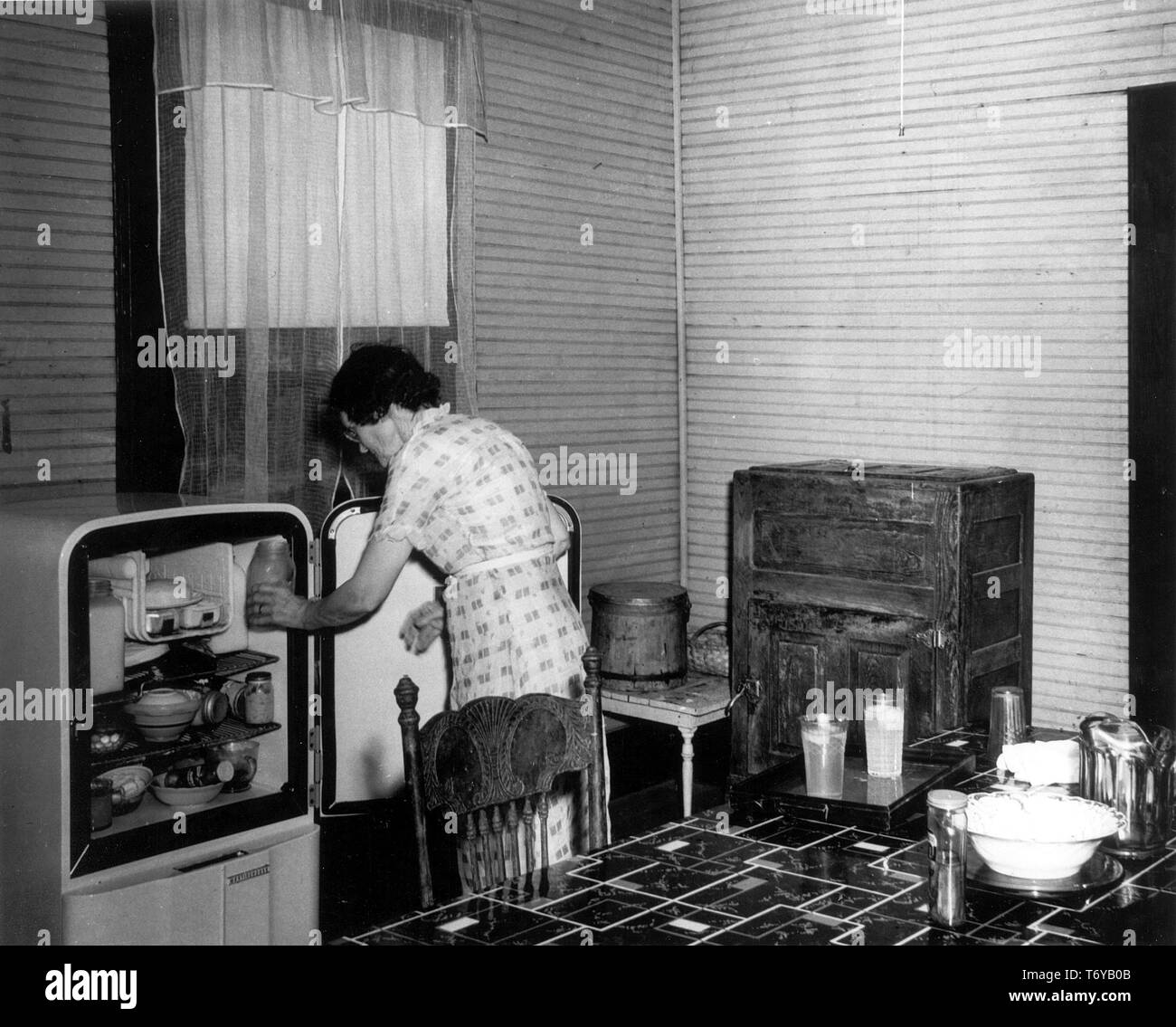Una donna si erge in una cucina, la rimozione di un vaso da un refrigeratore elettrico, con un pre-ghiacciaia elettrica in background, Putnam County, Georgia, 1941. Immagine cortesia del Dipartimento Americano di Energia. () Foto Stock