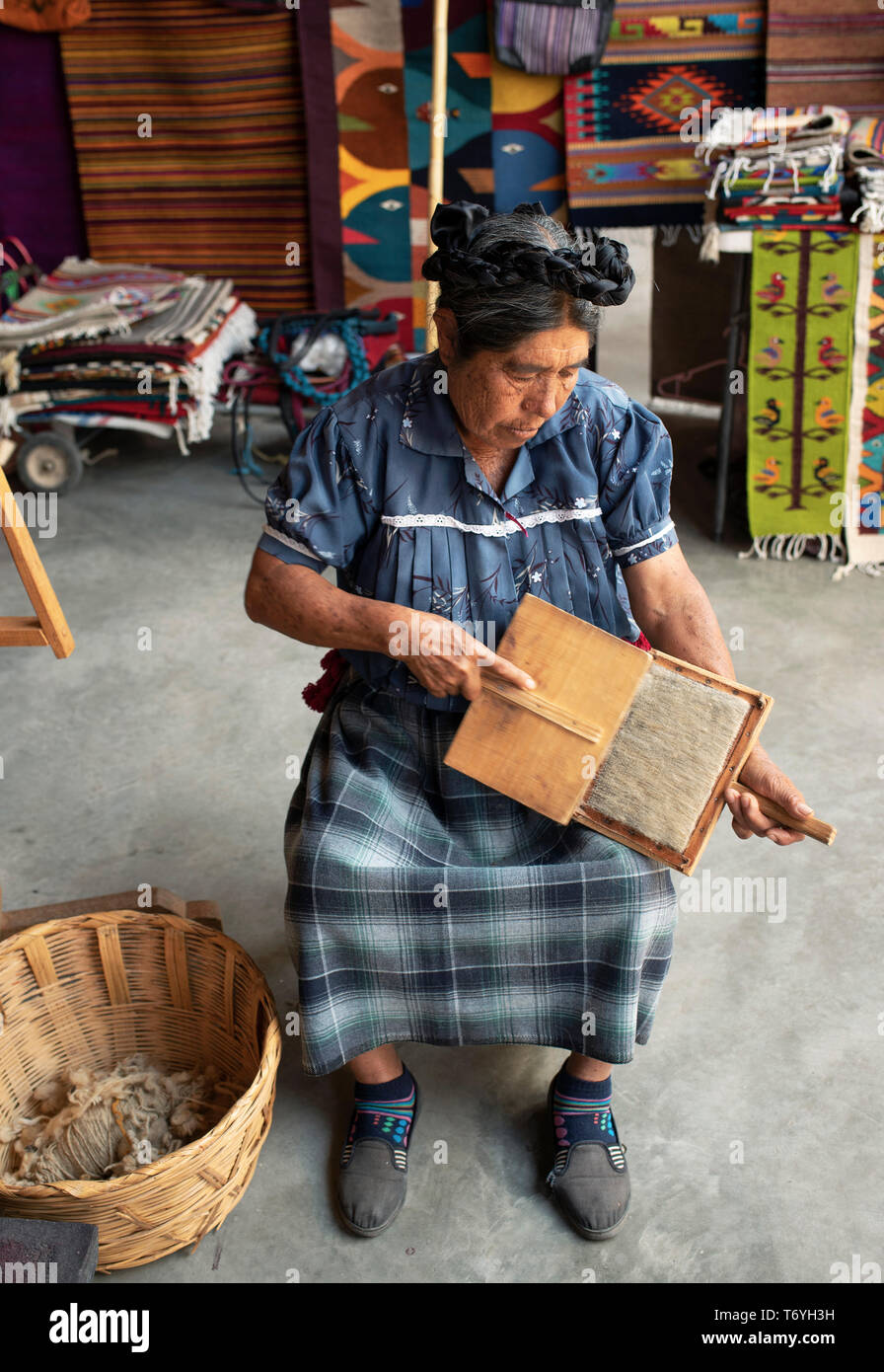 Zapoteco donna pettinatura della lana grezza per preparare la filatura è sulla ruota per rendere al filato. Teotitlan del Valle, Oaxaca, Messico. Apr 2019 Foto Stock